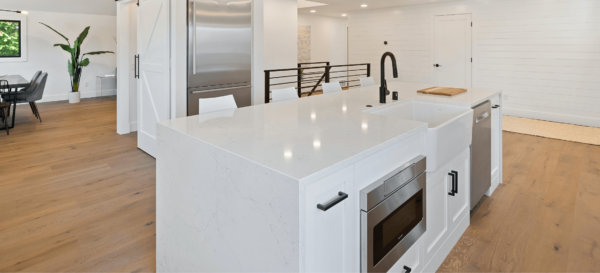 Modern kitchen with marble island, stainless steel appliances, hardwood floors.